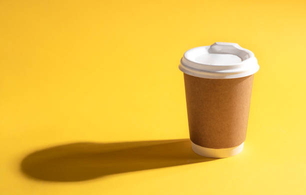 istock Disposable paper cup on a yellow background, close-up. 1490710805