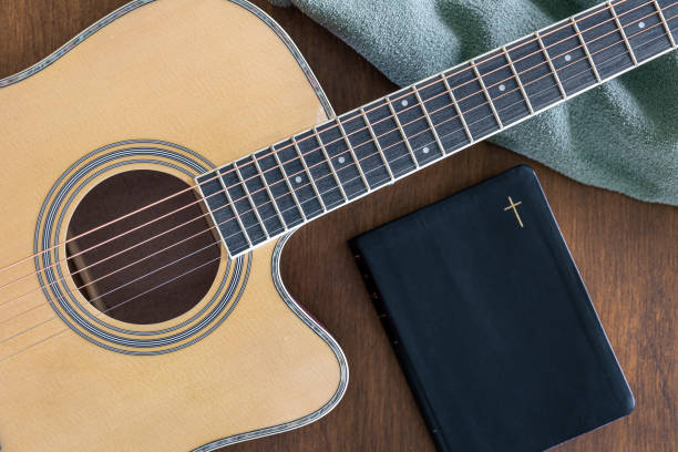 istock Guitar and bible book on wooden background, top view. 1490710874
