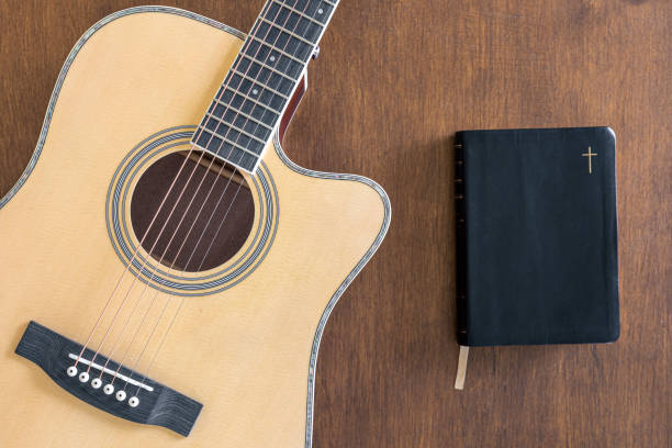 istock Guitar and bible book on wooden background, top view. 1490710878