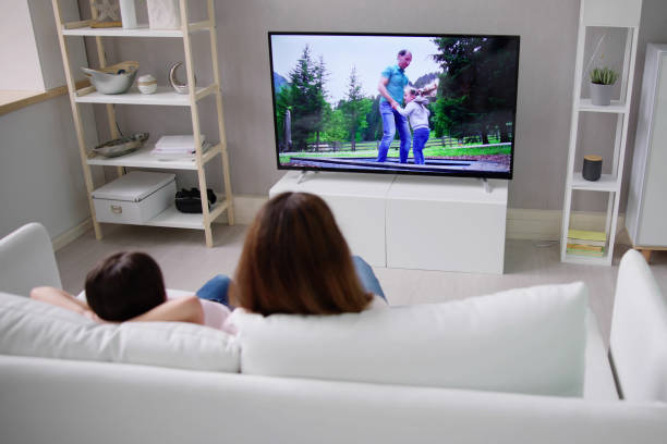 istock Smiling Mother And Daughter Watching Television 1490711813