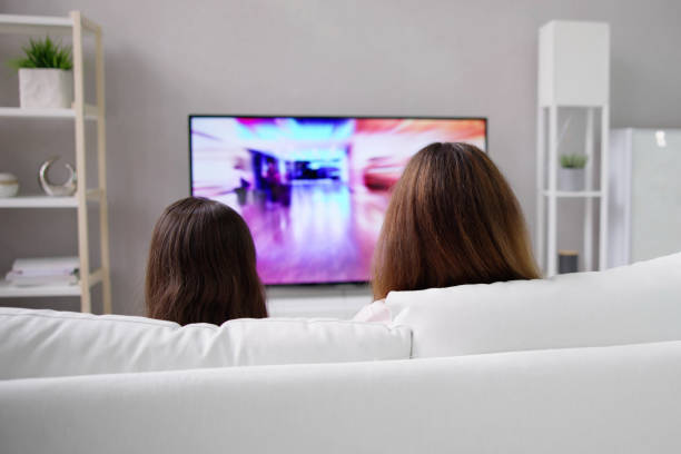 istock Smiling Mother And Daughter Watching Television 1490711825