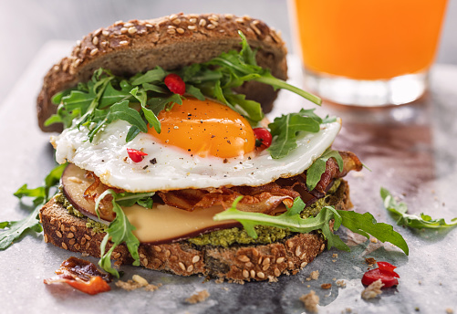 A breakfast sandwich on a white plate with blurred background.