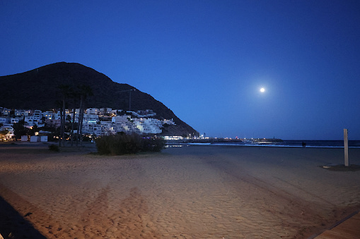 The charming town of San Jose is nestled within the Cabo De Gata park in Almeria, Andalusia, Spain.  This view shows a white village illuminated from a full moon.