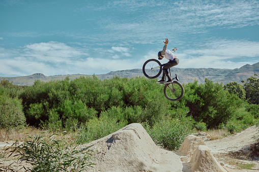 Attractive view of mountain biker flying in the sky, downhill riding in the mountain trail.