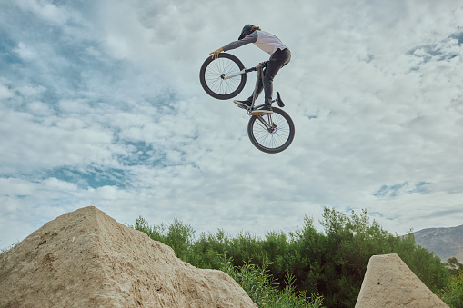 Cycling jump, sports or mountain bike man with air trick for fun, exercise or training for speed travel race. Dirt ramp, bicycle nature flight or extreme athlete with freestyle action