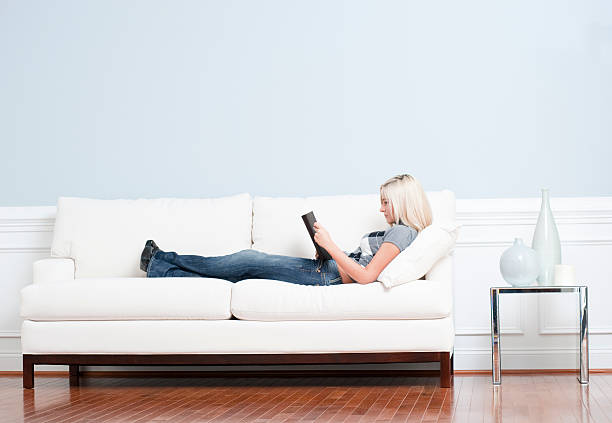 Femme couché sur un canapé avec livre - Photo