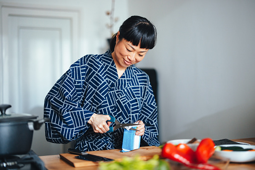Beautiful Asian woman opening tofu in the kitchen ready to cook.