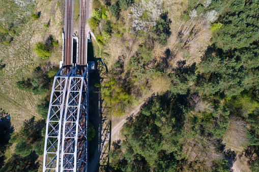 Railway bridge and tracks in the forest. Sustainable transportation. Metal industry. Steel structures. Communication between cities and in the provinces. Aerial photo.
