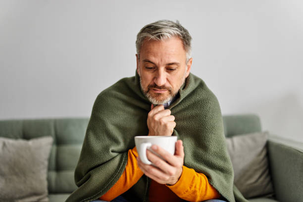 istock A senior man freezes and covers himself with a blanket while holding a cup of tea. 1490715754