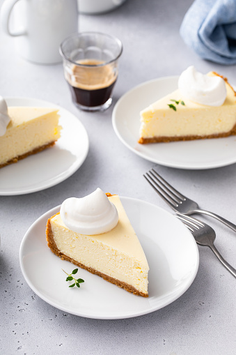 Slice of a traditional New York cheesecake with dollop whipped cream