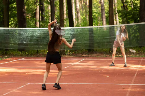 Photo of teenager sport outdoor, two girls play badminton in the park in nature on a sunny summer day, badminton competition