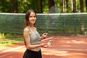 badminton, teenager girl on sport court, player with racket in the park in summer