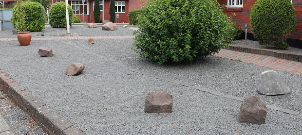 a modern front yard with gray granite stones and plants