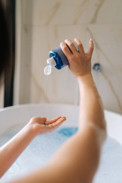 istock Vertical back view of unrecognizable young woman taking bubble bath, pouring shampoo into hand, enjoying home spa procedure, selective focus. 1490721000
