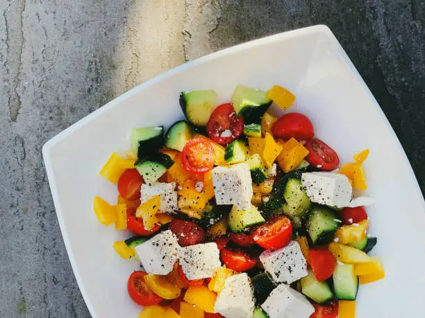 Fresh vegetable greek salad with cherry tomatoes, bell pepper, cucumber, feta cheese, olive oil and seasonal spices, healthy food diet and delicious meal recipe concept