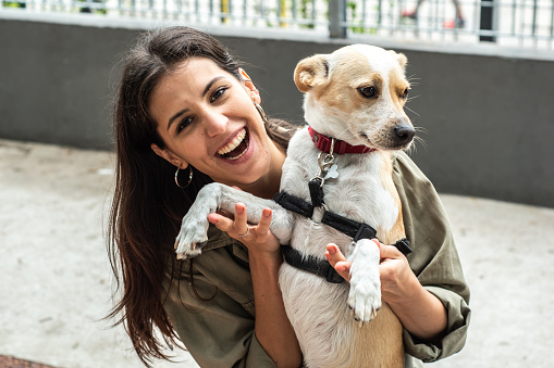 Portrait of a young woman playing with her pet in the city