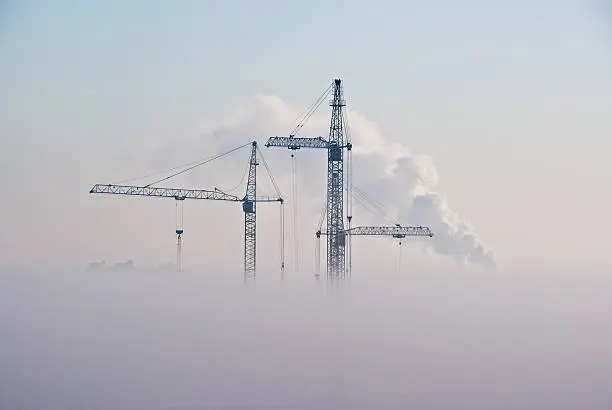 Cranes and buildings in clouds