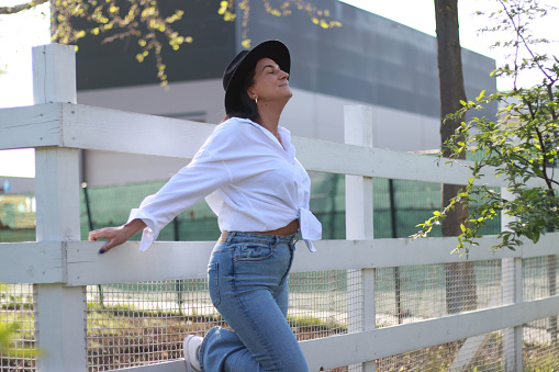 Young fashionable woman with hat in jeans and white shirt