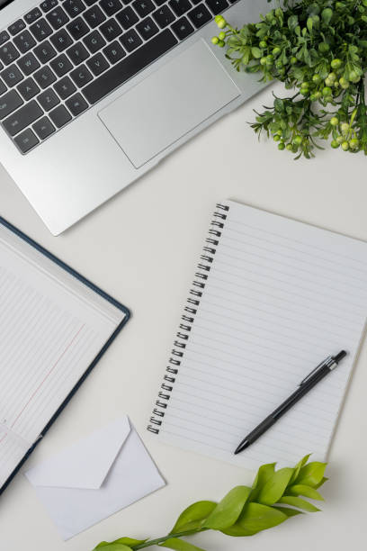 istock White office desk table with blank notebook, laptop and other office supplies. Top view with copy space. 1490729876