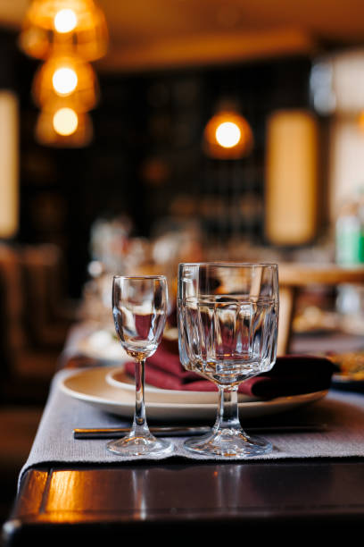 istock Festively table setting in a restaurant, close up two empty shiny wine glasses. Served table for wedding, birthday, anniversary party. Plates, cutlery, red napkins on wooden table. Soft electric light 1490735210