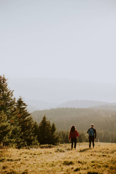 istock Smiling couple walking with backpacks over green hills 1490735223