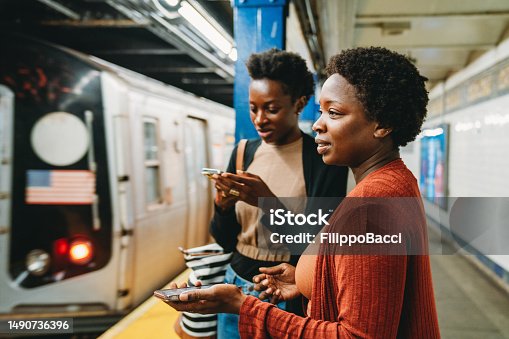 istock Two friends are using smart phones in a subway station, waiting for the train 1490736396