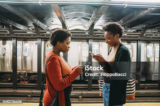 istock Two friends are using smart phones in a subway station, waiting for the train 1490736406