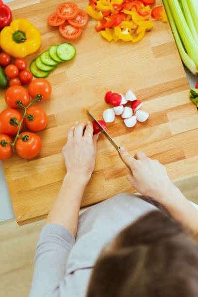 istock Woman slicing vegetables on cutting board 1490736606