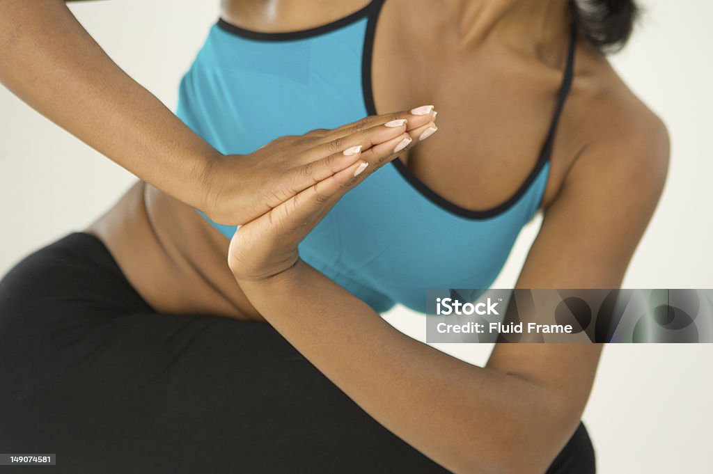 African American woman practices yoga African American woman does yoga twists against a white background - no face visible. Active Lifestyle Stock Photo