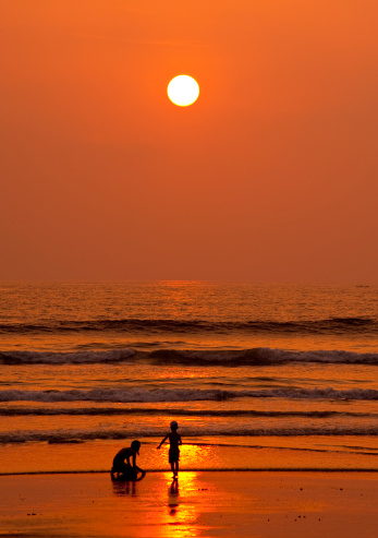 Children playing at the beach in sunset