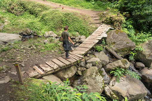 One men hiking over small wooden bridge in rain forest in Faial da Terra, the path to the waterfall Salto De Prego. Sao Miguel island in Azores