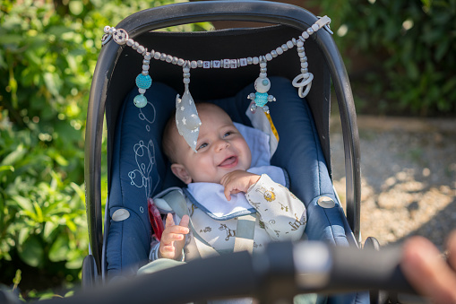 Laughing happy baby boy sitting in a stroller