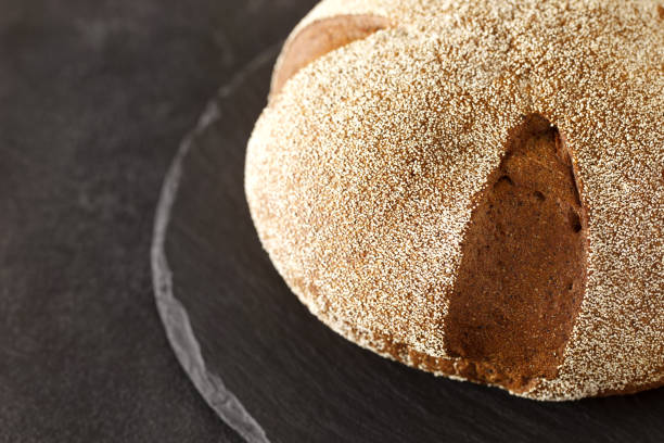 istock Dark round bread sprinkled with semolina, on slate stone plate round, selective focus 1490751574