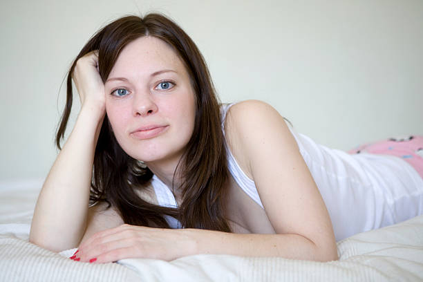 serious woman with long hair lying on bed stock photo