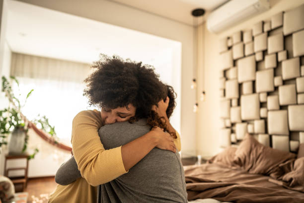 Sad young woman embracing her girlfriend after a bad news in the bedroom at home Sad young woman embracing her girlfriend after a bad news in the bedroom at home candid bonding connection togetherness stock pictures, royalty-free photos & images