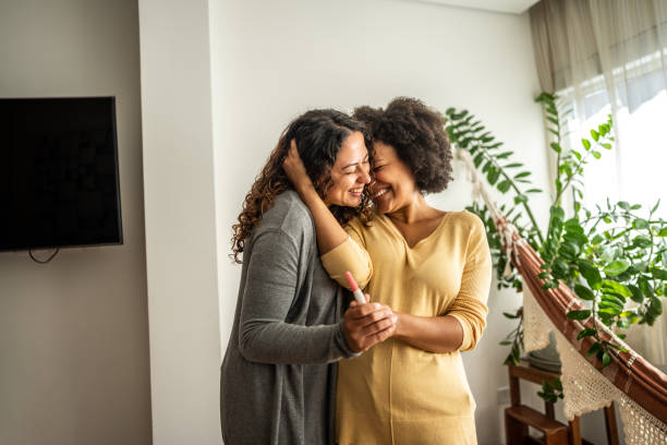 leszbikus pár, akik otthon terhességi tesztet tartanak - termékenység témájú stock jellegű vizuális alkotások, jogdíjmentes fotók és képek
