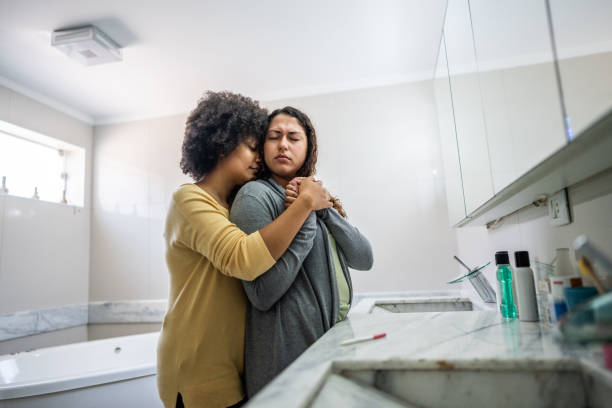 Young woman consoling her sad girlfriend after a bad news about the pregnancy on bathroom at home