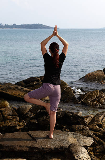 istock Woman doing yoga on rock, looking at sea 149076034
