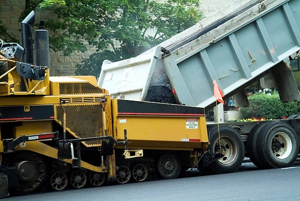 istock Truck dumping hot asphalt into paving machine 149076167