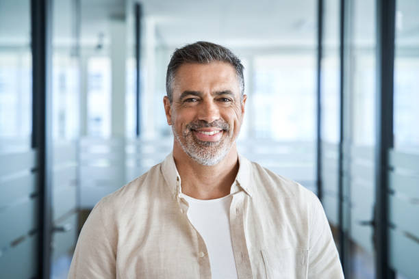 Headshot portrait of confident handsome mature middle age businessman at office Headshot close up portrait of indian or latin confident mature good looking middle age leader, ceo male businessman on blur office background. Handsome hispanic senior business man smiling at camera. headshot stock pictures, royalty-free photos & images