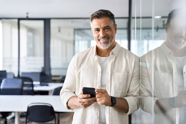 istock Middle aged hispanic employee standing with phone and looking at camera. 1490764606