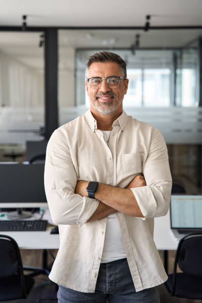 Vertical portrait of senior business man with crossed arms smile at camera stock photo