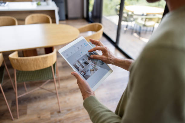 Man monitoring his smart home using a security system on his tablet Close-up on a man monitoring his smart home using a security system on his tablet indoor security camera stock pictures, royalty-free photos & images