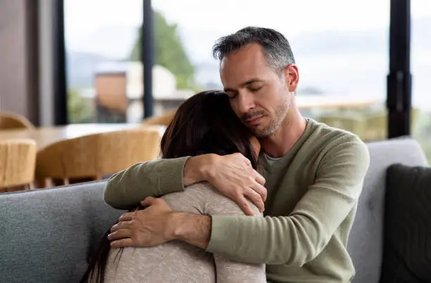 Loving Latin American man comforting his wife grieving and crying at home - lifestyle concepts