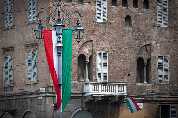 Two italian flags hanging from a brick building in amsterdam, netherlands, reflecting in the windows