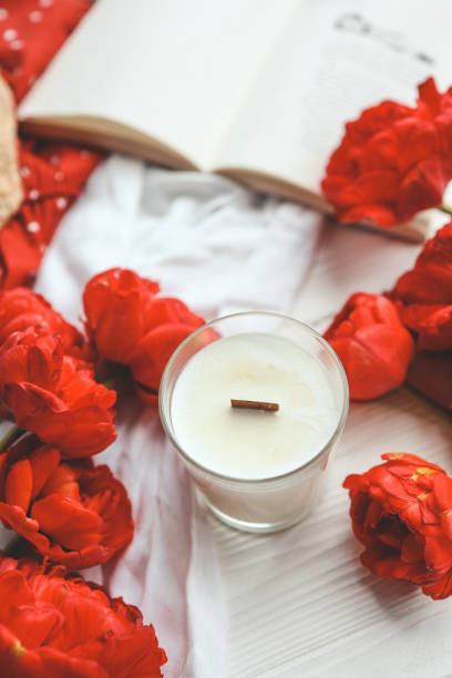 istock Candle, tulips and open book in home interior. 1490766807