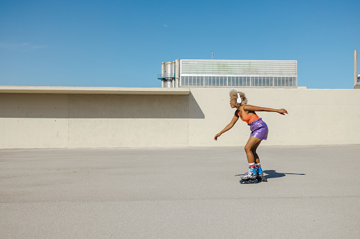 Blonde woman listening to music and riding on rollers. Healthy lifestyle concept