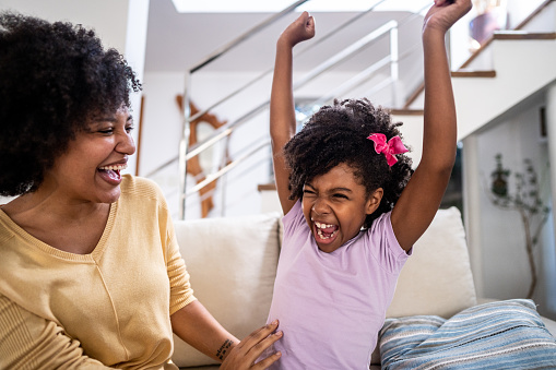 Girl child celebrating with her mother on sofa in the living room