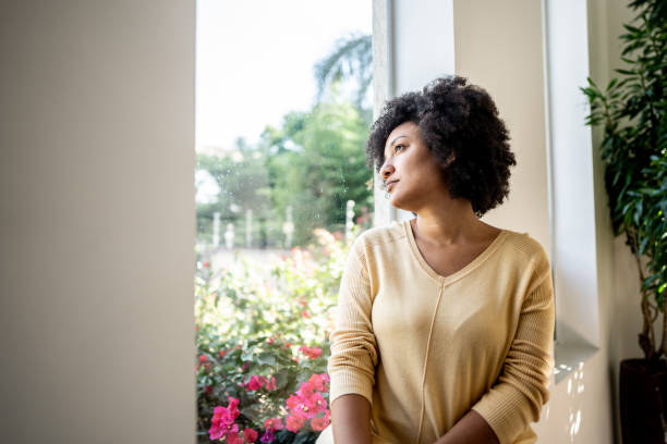 istock Young woman contemplating while looking through the window at home 1490767770