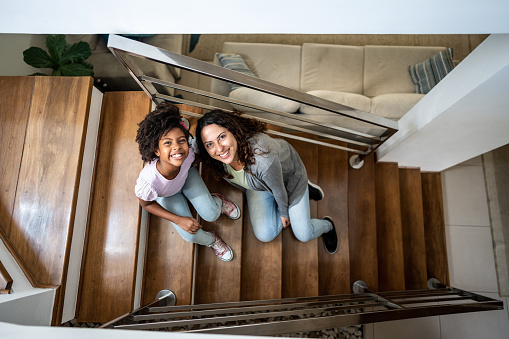 Portrait of a mother and daughter sitting on staircase at home